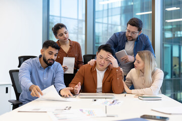 Business team comforting stressed asian colleague in office meeting