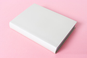 Closed generic blank book isolated on pink background. Template mock up
