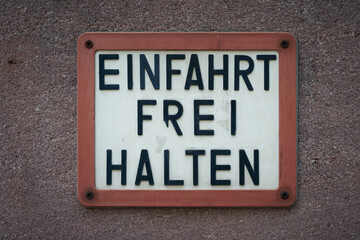 Schild an einer Hauswand mit der deutschen Aufschrift Einfahrt freihalten
