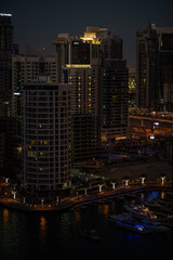 Obraz premium Night view of Dubai Marina with illuminated skyscrapers, modern architecture, and city lights reflecting on the water. 