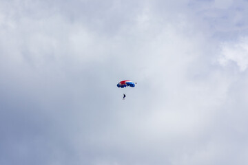 Silhouette of parachutist flying on cloudy sky. Adrenaline, dangerouns sports background