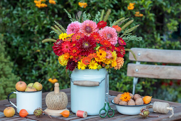 Garten-Arrangement mit Blumenstrauß mit roten und orange Dahlien und Zinnien, Walnüssen und...