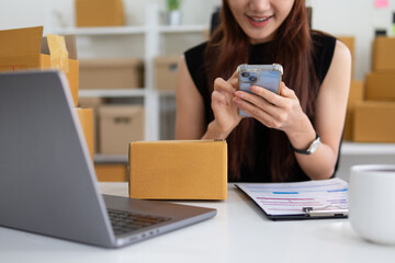 A female entrepreneur is communicating over the phone to check a parcel before delivering it to a...