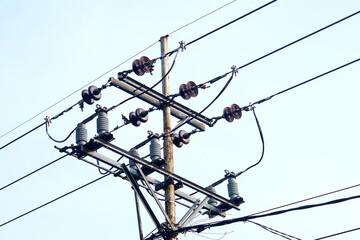 Electric power pole with wires and insulators against a clear blue sky, symbolizing energy,...
