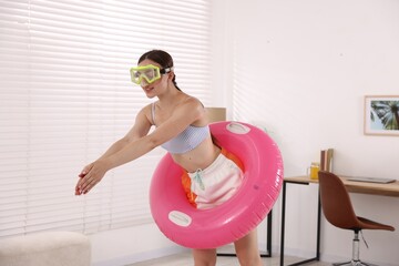 Woman in diving mask with inflatable ring having fun at home. Dreaming about vacation at sea