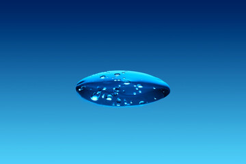 A drop of cosmetic product or serum on a blue background.