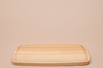 Empty wooden cutting board on beige background, perfect for food presentation, kitchen design, culinary template, recipe mockup, or healthy lifestyle cooking concept.