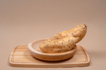 Fresh Cilembu sweet potatoes placed in a wooden bowl on a cutting board, showcasing Indonesian traditional food, organic nutrition, and healthy natural lifestyle.