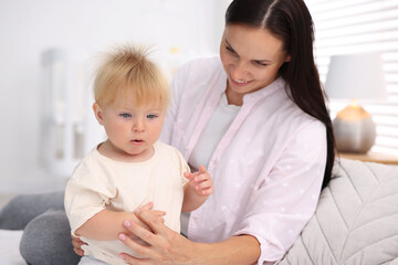 Mother and her cute little baby on bed in room
