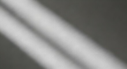 Photo of diagonal light streaks casting shadows on a textured grey surface