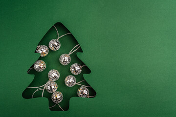 Shiny disco ball string lights glow inside a green Christmas tree paper cutout, blending festive cheer with modern, party-inspired style. Ideal for festive greeting cards, holiday banners