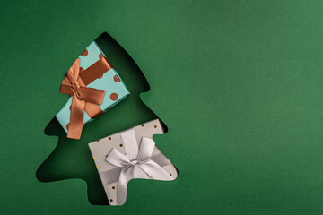 gift boxes with a red bow placed in a green paper Christmas tree cutout, symbolizing festive cheer and holiday giving. Ideal for festive greeting cards, holiday banners