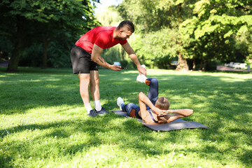 Young woman exercising with professional personal trainer outdoors