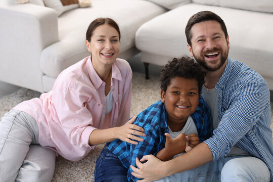 Adoption. Happy parents with their son on floor at home