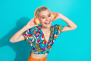 Young woman enjoying her favorite music on headphones, wearing stylish vibrant clothes, smiling...
