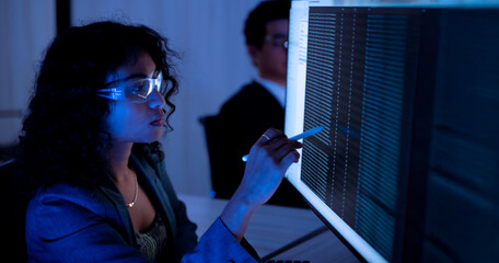 Two software developers collaborating at night, focusing on code review and debugging process on a computer screen, representing teamwork, innovation, and modern software development workflow.