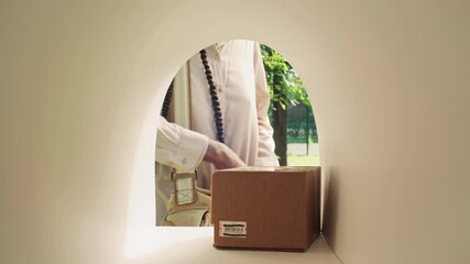 Unrecognizable Black female postal worker placing cardboard boxes into mailbox while standing outside in sunny park during delivery route. View from inside of mailbox