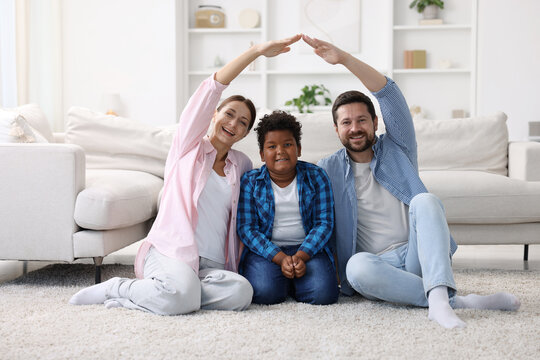 Adoption. Happy parents covering their son on floor at home