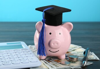 Scholarship. Graduate hat, piggy bank, calculator, dollar banknotes, coins and pen on wooden table...