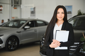Saleswoman holding clipboard in car dealership showroom