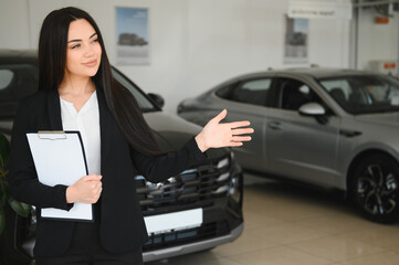 Saleswoman showing new car in dealership