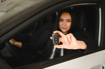 Businesswoman showing new car key while sitting inside vehicle