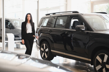 Saleswoman presenting new black suv in dealership showroom
