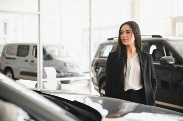 woman standing near car in dealership showroom