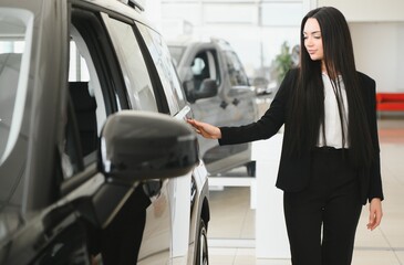 Saleswoman showing new car to potential customer in dealership