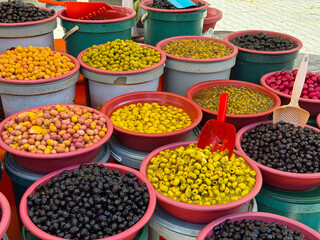 Various olives in buckets displayed on outdoor market stall. Agriculture, farming, and seasonal food produce with nutrition and traditional lifestyle.