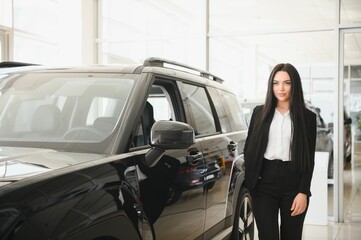 woman presenting new black car in dealership