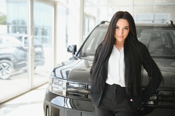 woman posing with new black car in dealership