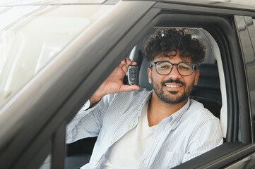 Happy man showing car key sitting in new vehicle