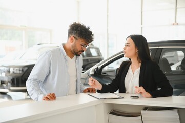 Saleswoman helping customer buying new car in dealership