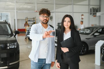 Customer showing new car key with saleswoman in dealership