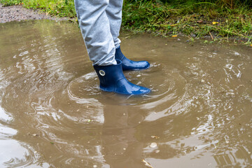 Rubber boots in a puddle.Measure the puddle with your feet.After the rain.