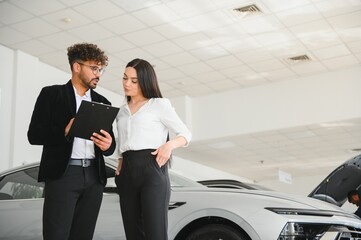Car salesman showing contract to female customer in dealership