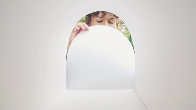 Curly-haired woman in lavender sweater looking into empty mailbox in park while expecting letters