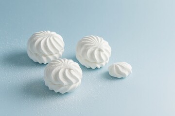 Winter minimal still life with zefir marshmallows on pastel cool blue background decorated with light sugar frost, airy composition with copy space for seasonal culinary editorial projects