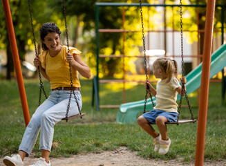 Mom and daughter looking at each other while sitting on swing