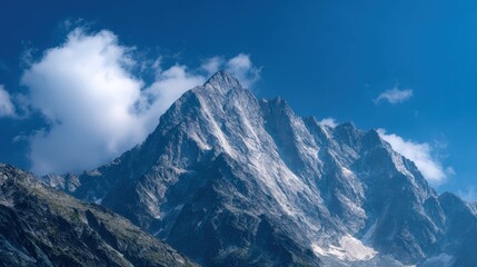 Towering jagged mountain peaks under a clear vibrant blue sky with a few scattered clouds
