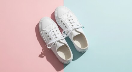 Pair of white canvas sneakers with tied laces on a split pink and blue background with shadows white sneakers