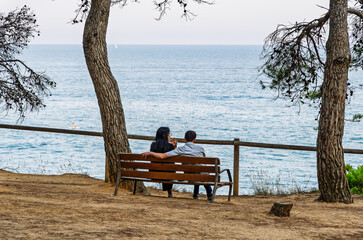 Couple sitting on a bench overlooking the sea
