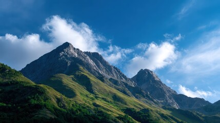 Fototapeta premium A vast mountain range with jagged peaks under a clear vibrant blue sky with scattered clouds