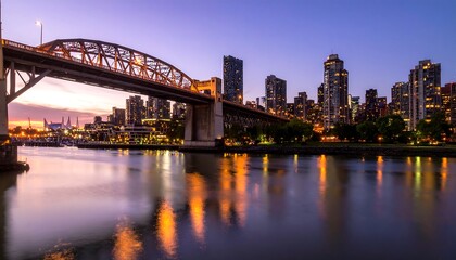 Fototapeta premium City skyline at twilight over water and bridge