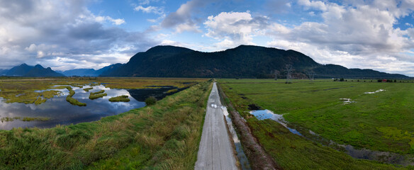 Scenic Road and Wetlands with Mountains in BC, Canada Under Cloudy Sky