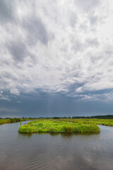 Dark sky with rain showers over the water rich Dutch polder landscape, , evoking serenity and...