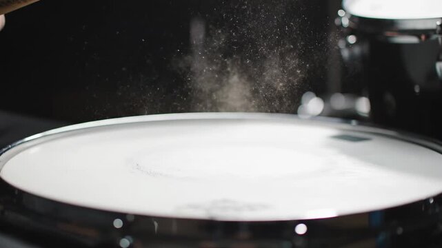 Drummer Hitting Snare Drum Close Up - A close-up shot of a drummer's sticks hitting a snare drum, creating a cloud of dust particles in the air. The focus is on the impact and the resulting effect.
