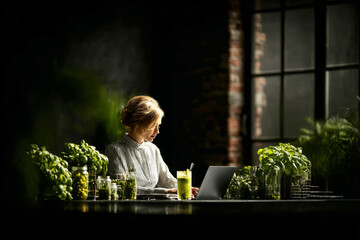 A person is engaged in work at a coworking space, sipping matcha. Lush green plants surround the workspace, creating a serene and refreshing atmosphere during a work session
