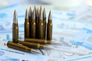 United Arab Emirates dirham currency money bills and rifle bullets. The concept of warfare and gun selling